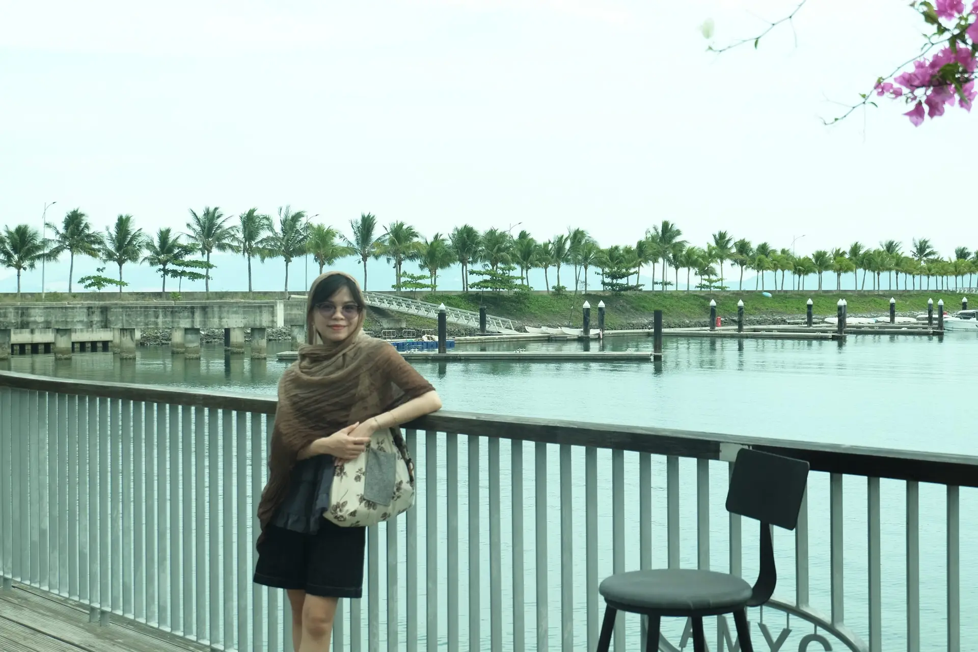 Vy Vy đứng dưới khung cảnh xinh đep trùm một chiếc khăn màu nâu trên đầu